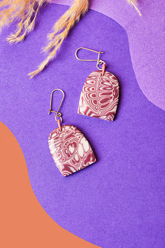 Dome earrings in soft burgundy marble. Calm, wearable contrast.