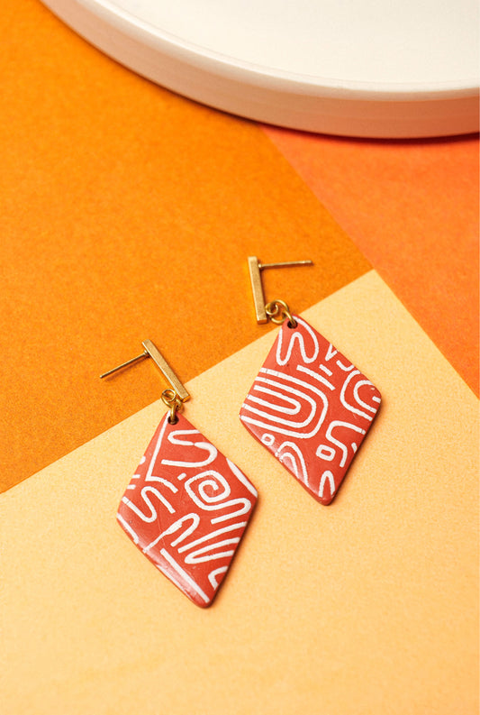 Burnt red clay with white linework. Structured, offbeat, wearable.