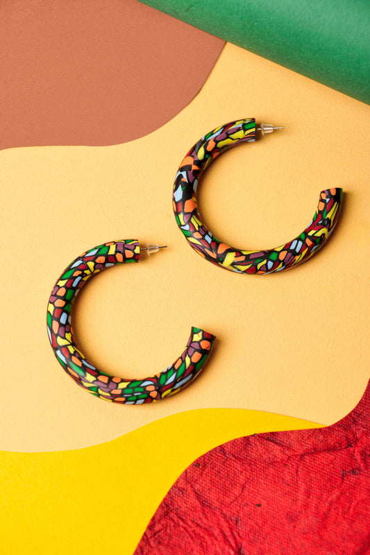 Graphic hoops in black clay with a burst of colour. Bold, lightweight, and handmade in Berlin.