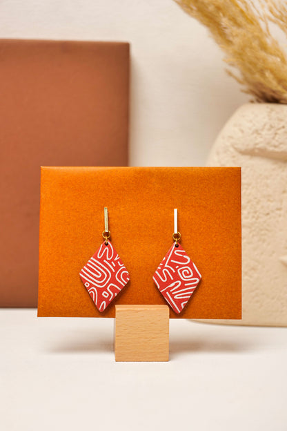 Burnt red clay with white linework. Structured, offbeat, wearable.
