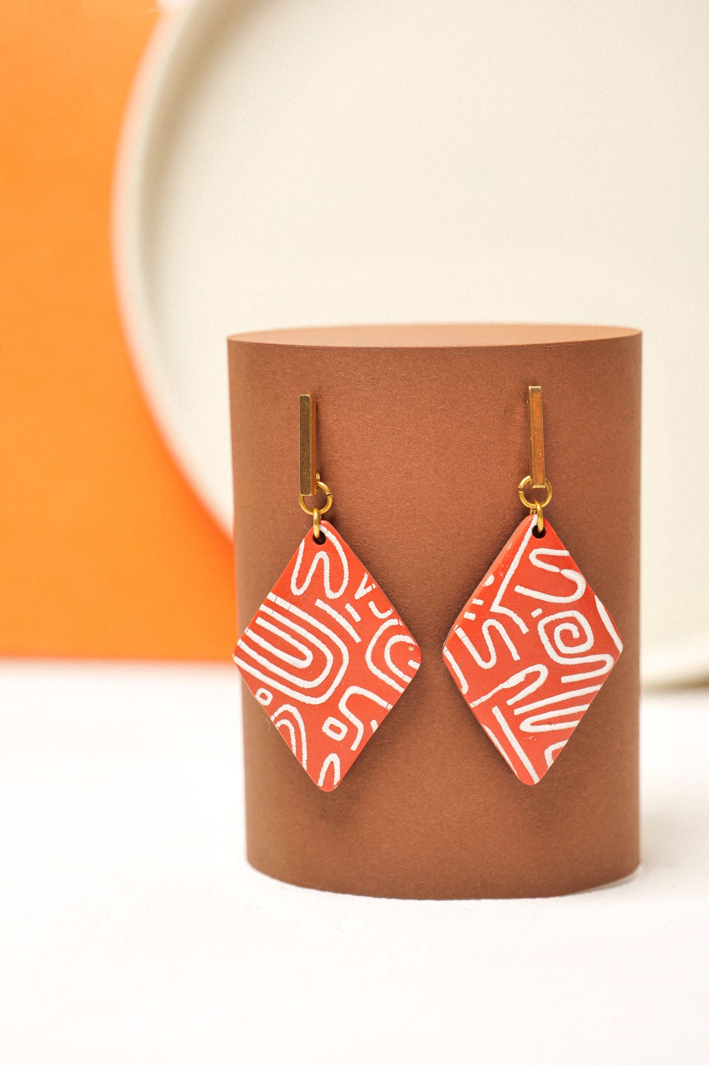 Burnt red clay with white linework. Structured, offbeat, wearable.