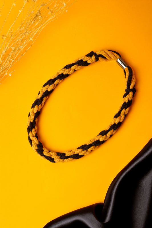 Hand-knotted cotton cord necklace in mustard and black. Soft, structured, and bold.