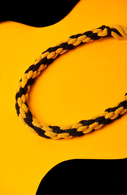 Hand-knotted cotton cord necklace in mustard and black. Soft, structured, and bold.