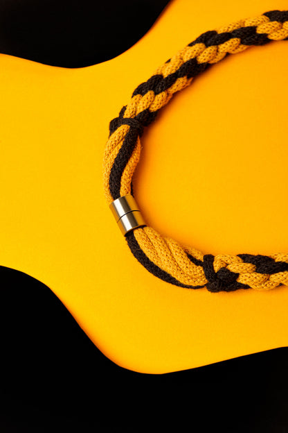 Hand-knotted cotton cord necklace in mustard and black. Soft, structured, and bold.